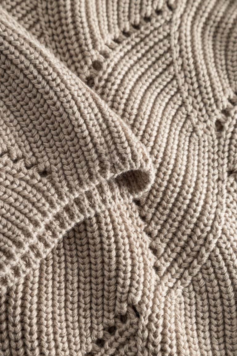 ekologisk väst mönsterstickad bomull lång oversize beige närbild stickning