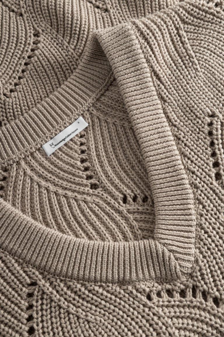 ekologisk väst mönsterstickad bomull lång oversize beige närbild v-hals
